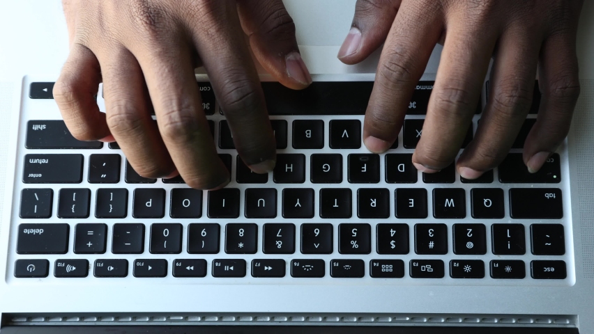 Close-up of a black African man typing with his hands on a laptop. Hands type text on the keyboard to send emails and surf in a web browser. Royalty-Free Stock Footage #1083521167