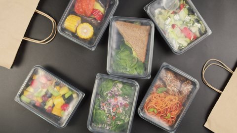 Packaging take away meals into paper bags top view, Food delivery in disposable containers, catering, balanced nutrition. Fresh cooked portions in lunch boxes, vegetarian dishes. Healthy eating.