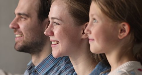 Side view happy millennial couple parents and little child girl standing in row looking forward turning heads to camera by one. Close up profiles of mother father preteen daughter kid smiling faces