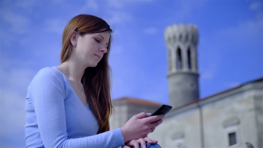 Attractive female person sit in front of famouse St. Clement church re-named in to Mary of Health, placed in Piran, Slovenia. Sunny day with blue sky.