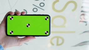 Big sale. Woman using a smartphone green screen on mall with sale background.. Hands with a mobile phone, checking stock market data. Scrolling through, on a touch screen device - Powered by Shutterstock - Get 15% off with code: PIKWIZARD15