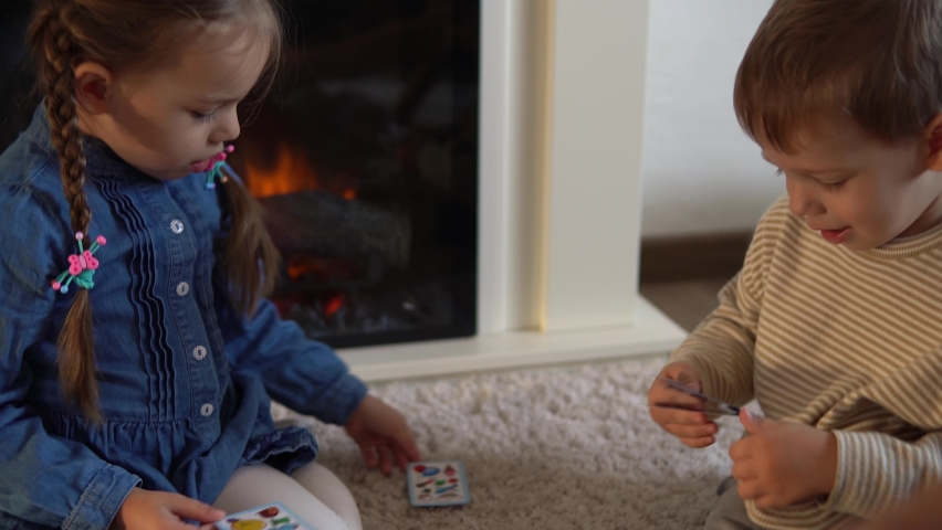 Childhood, education, hobby, family, friends, friendship concept. Happy young mother mum babysitter with little preschool kids children spend time playing card game on floor at home by fireplace Royalty-Free Stock Footage #1083535795