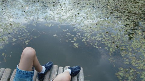 teen boy lies on a pier near the lake, relaxes at summer, connect with nature