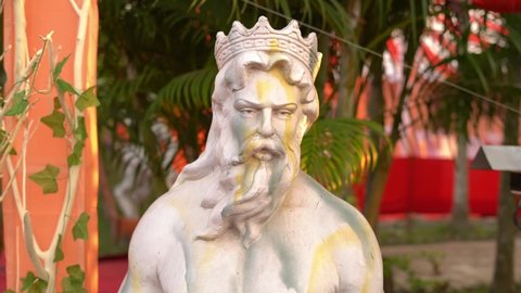 monumental statue of God Poseidon on the beach, against the backdrop of a garden