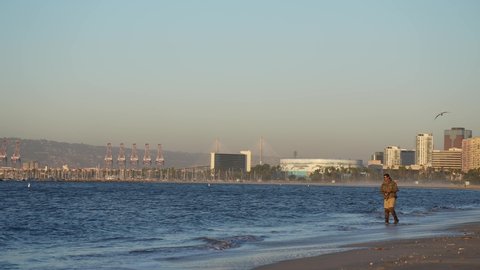 Long Beach , California , United States - 11 25 2021: Long Beach, California USA - November 25, 2021: Establishing shot of the beach with a man fishing and the city in the background