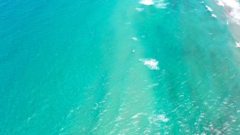 A cool drone shot of crystal clear waves rolling into a South Florida Beach.