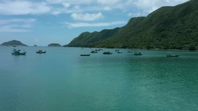 aerial drone shot of Con Dao island, Vietnam. Harbour with floating fishing boats in the bay between mountains under blue sky 