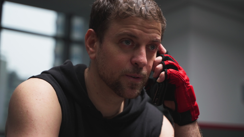 after training man sitting in the gym take a break talking on the mobile phone