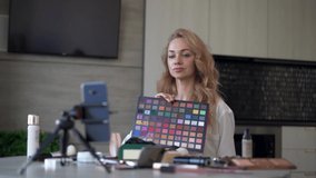 Beauty, cosmetics, e-commerce and blogging concept. Beautiful professional young woman makeup artist talks about colors on a palette while recording a video review of beauty products