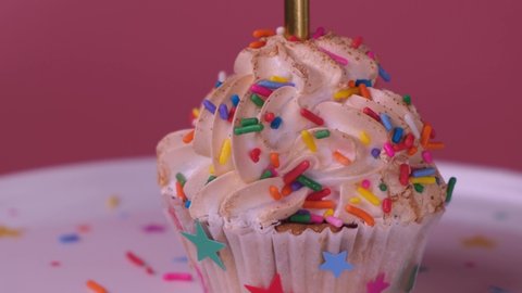 Spinning cupcake or cake with a candle on a pink background, the concept of celebrating the birthday of a child or girl.