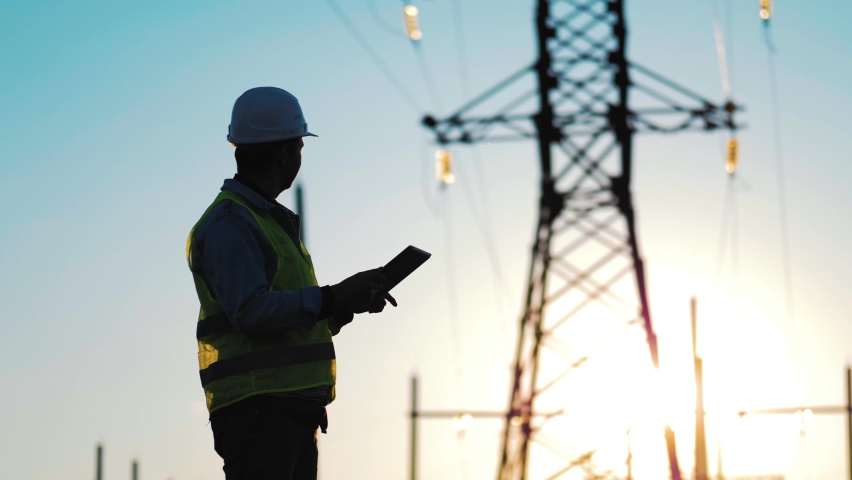 Industry energy business concept. Silhouette electrical engineer a working near tower with electricity at sunset time. Electrical worker inspect voltage electricity pylon. Power generation industry. Royalty-Free Stock Footage #1083560329