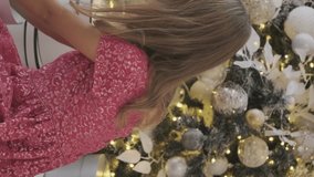 Vertical Video. Adorable Little Girl Getting Cute Christmas Kitten Present Indoors. Friendship Between Human and Pet. Christmas and New Year Celebration Concept