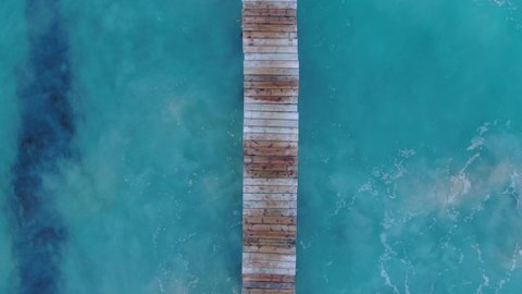 
aerial view of a wooden pier on Majorca beach. Cenital aerial view of the Mediterranean Sea with a beautiful dock  in Majorca Island, Balearic Islands, Spain Vacation, summer and relaxation concept.