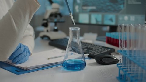 Scientist working with micro pipette and beaker to mix substance in test tube for biochemical experiment in laboratory. Researcher using scientific instruments and lab glassware. Close up