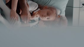 Vertical video: Close up of african american nurse talking to patient and his family in hospital ward, explaining diagnosis and treatment. Assistant discussing about healthcare with man and relatives.