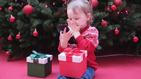 Little girl using smart phone talking to family congratulates Merry Christmas by video call.