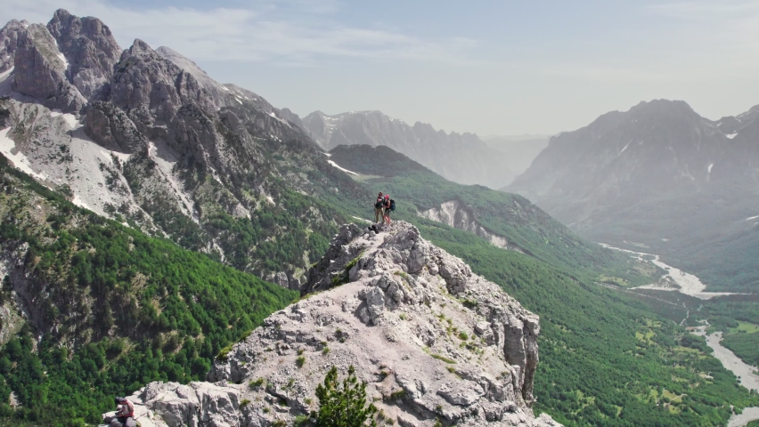 Flying around pair of hikers on the top of mountain. Aerial drone shot of man and woman travel with backpacks in the mountains. Valbona pass, Albanian Alps Royalty-Free Stock Footage #1083568993