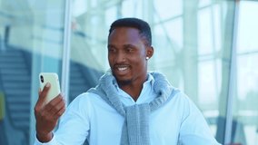 African American man use smartphone for video call speaking stand outside near airport smiling. Portrait confident young leader. Outdoors. Slow motion