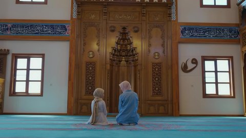 Muğla, Turkey-06.01.2021:A Muslim mother and her little daughter pray in a hijab mosque. Little girl and her mother praying to god.Islam, religion and worship concept. 