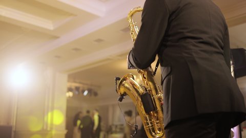 Saxophonist play on golden saxophone. Live performance. Saxophone player performing a solo on party. Musician playing alto saxophone on a gig