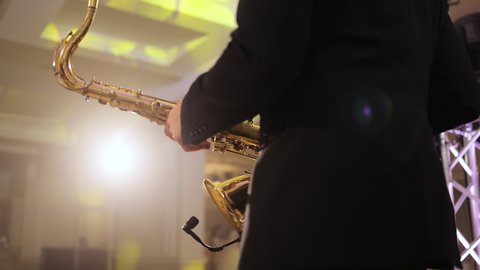 Saxophonist play on golden saxophone. Live performance. Saxophone player performing a solo on wedding party. Musician playing alto saxophone on a gig. Wedding day