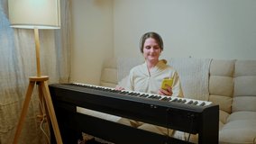 Happy woman musician with piano looking at mobile phone at home on sofa in living room