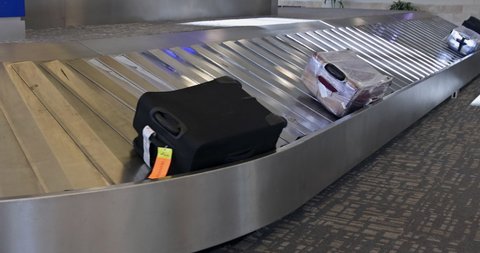 Baggage pickup carousel at the airport with wheeled suitcase on a luggage belt