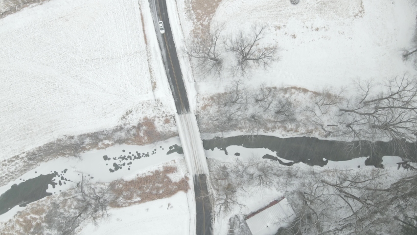 Snowy trail up mountain in western Wisconsin. Highway bridge of creek. Farm house and barn nestled into mountain. 