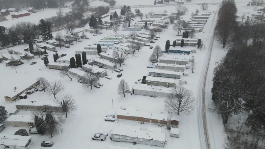 Aerial view of rural mobile home court in western Wisconsin. Snow covered road. Tree lines in the valley. 