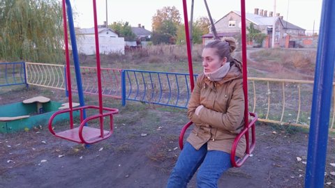 A woman on a swing watching children and talking