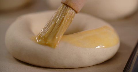 Baker smears bagels by egg yolk with a brush. Baking the pastry, 4k 60p Prores