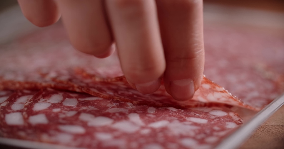 Woman takes thin slice of salami by fingers in slow motion. Cooking with pepperoni, 4k 60p Prores | Shutterstock HD Video #1083586324