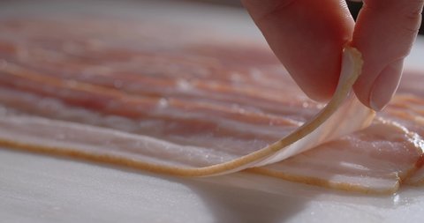 Chef tooks thin slices of smoked bacon in slow motion. Cooking with natural meat products, 4k 60p Prores