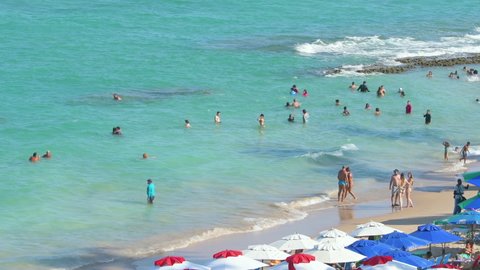 Ipojuca, PE, Brazil - October 15, 2021: bathers at Porto de Galinhas beach on a sunny day. View of the sea, the beach and the umbrellas. Tourist destination of the brazilian northeast.