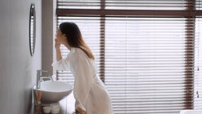 Oral Care Concept. Young Asian Woman Brushing Teeth In Bathroom, Millennial Female Standing Near Sink, Spit Out Toothpaste And Rinsing Toothbrush, Making Morning Dental Hygiene, Slow Motion Footage