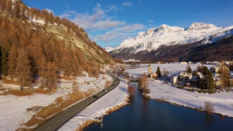 Aerial drone footage of the traffic along the lake Sils and Sils Maria village in winter in the Engadine valley in Canton Graubunden in the alps in Switzerland
