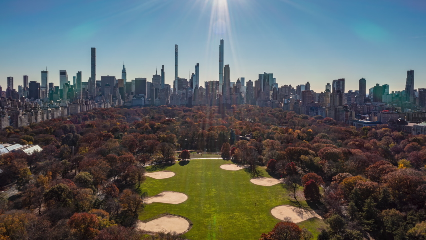 Forwards fly above Central park with autumn colour trees on sunny day. Wide hyperlapse with downtown skyscrapers in background. Manhattan, New York City, USA Royalty-Free Stock Footage #1083594934