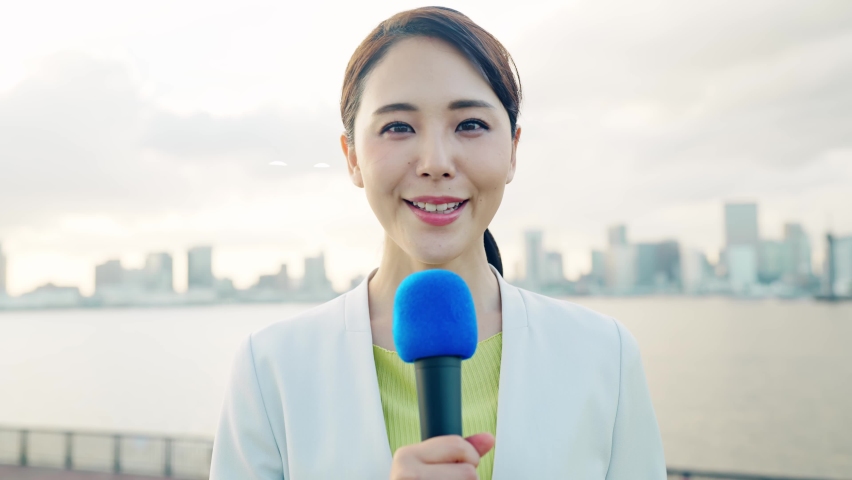 Young asian announcer reporting in front of the city. Royalty-Free Stock Footage #1083599119