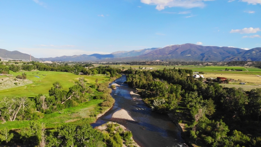 Shallow River Creek Landscape Lined With Vibrant Lush Green Trees In Colorado Rocky Mountain Valley. 4K Drone.