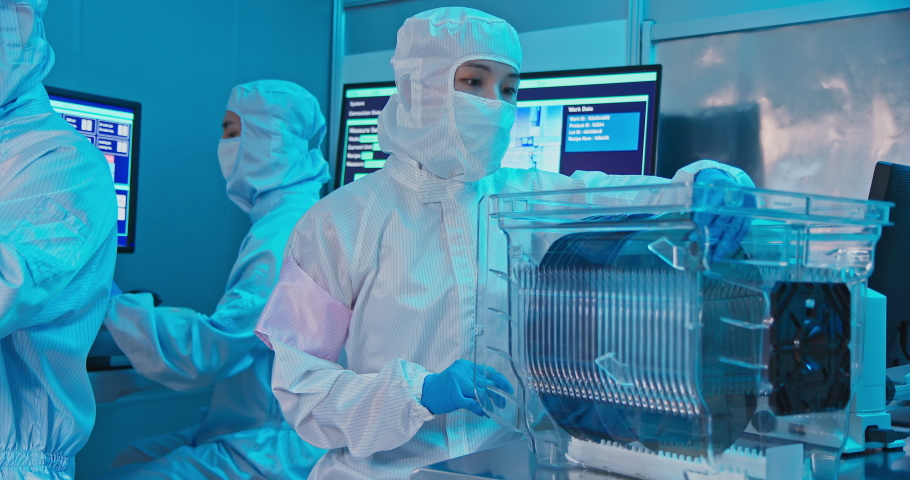 Asian female technician in clean room suit holds wafer that reflects many different colors with gloves and check it at semiconductor manufacturing plant | Shutterstock HD Video #1083600406