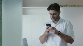 Young indian man holding smart phone using mobile apps watching funny video. Smiling man having fun chatting in social media. Asian male chatting with friend on Smart Phone white background studio.