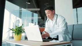 asian doctor advises patient online via video call using laptop and webcam. Remote consultation with a physician. man talking chat with colleagues Telemedicine, telehealth. modern surgery office