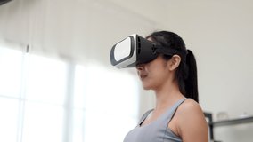Training with virtual sport at home. Young asian sport woman wearing sportswear workout exercise stretching put on vr glasses into virtual simulated world. Metaverse future digital cyber universe.