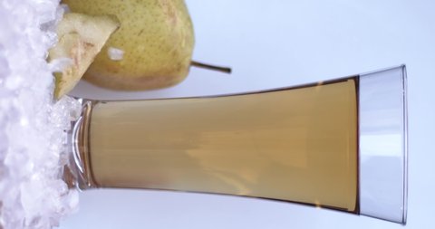 Sliced pears fall on the ice near a glass with pear juice on a white background. Slow motion, filmed on cinema camera, 8K downscale, horizontal frame, 4K.