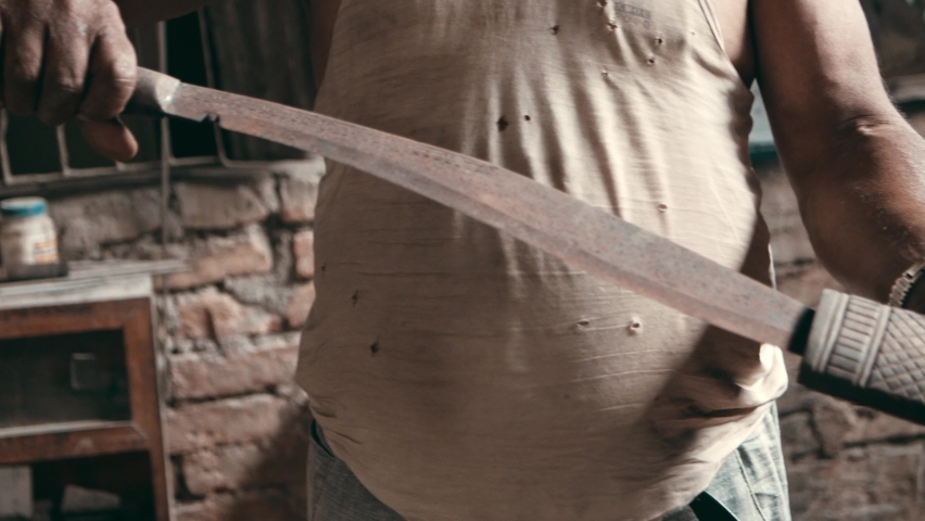 Man presenting old rusty kukri knife in wooden sheath