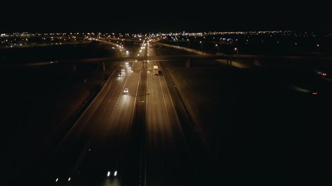 Drone shot of night traffic on a motorway showing cars and lanes of light with bridges and viaducts outside the city of Warsaw, Poland. Moving the camera forward.