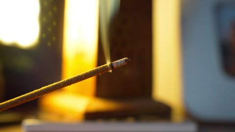 Incense sticks burning against the fireplace. Selective focus. Focus on incense stick and smoke.