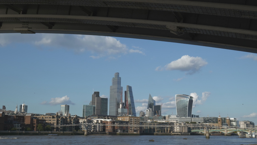 A view of central London skyscrapers from underneath a bridge.