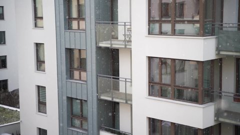 Slow-motion video of snow falling in the residential complex. Weather winter in the urban area. Snowing in front exterior modern condominium area.