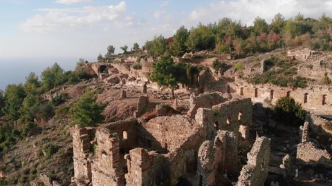 Ruins of ancient city in mountains. Landscape of ancient buildings of Syedra city, Turkey. Flight over old ancient city. Popular travel destinations